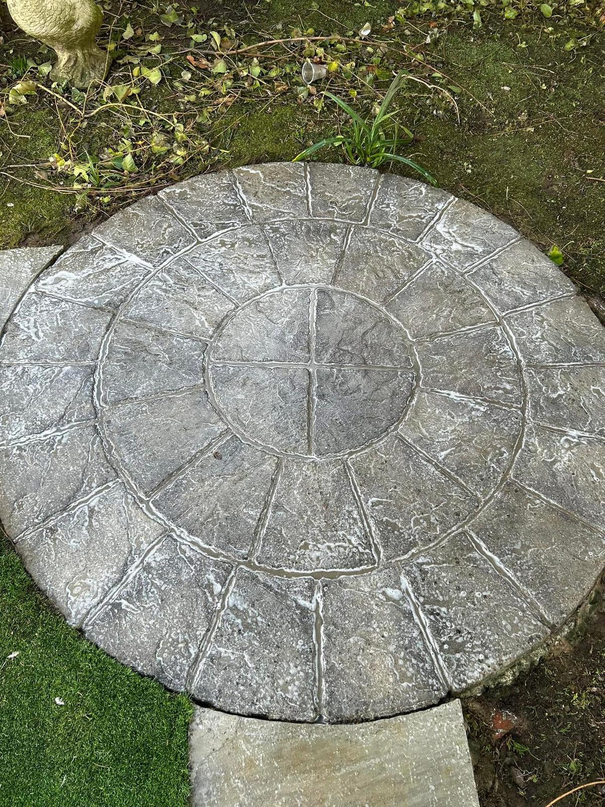 Circular patio feature after pressure washing — clean restored stone